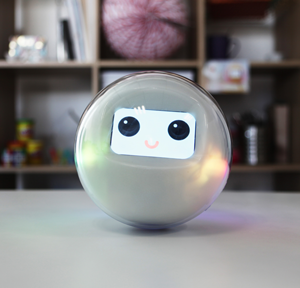 The smart toy Leka, a robotic sphere, rests on a table smiling through its digital interface.